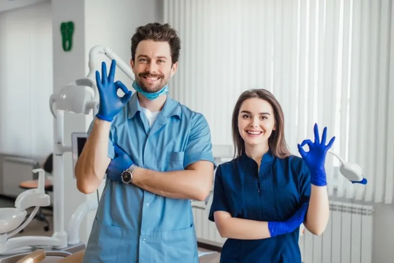 photo smiling dentist standing with arms crossed with her colleague showing okay sign 1 1 1